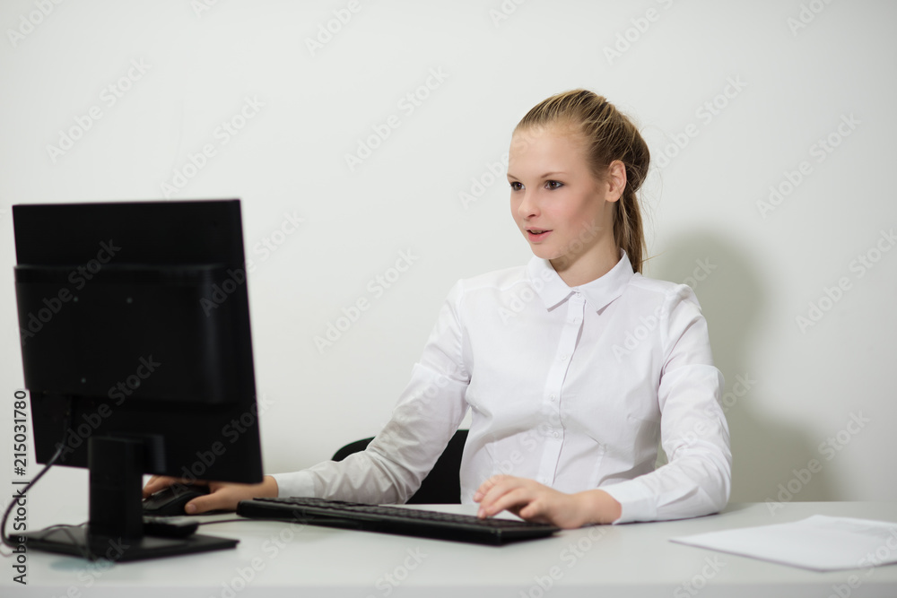 young girl businesswoman in casual clothes, sitting at a table closely look at documents, working at computer young girl businesswoman in casual clothes, sitting at a table closely look at documents, working at computer