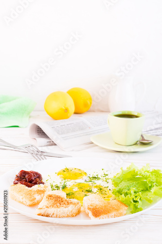 Scrambled eggs, fried bread, ketchup and lettuce leaves on a plate, cup of coffee and newspaper on the table. Ready-to-eat breakfast