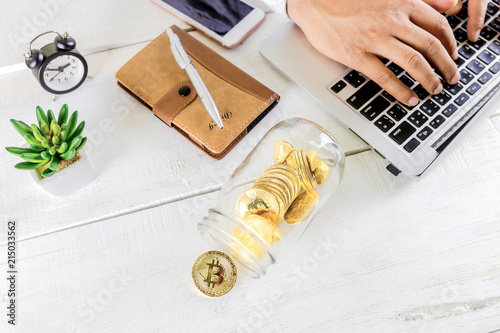 Bitcoin coin golden coin in the glass jar on wooden table ,Man using tablet for trading cryptocurrency or bitcion.Set of cryptocurrencies with a golden bitcoin photo