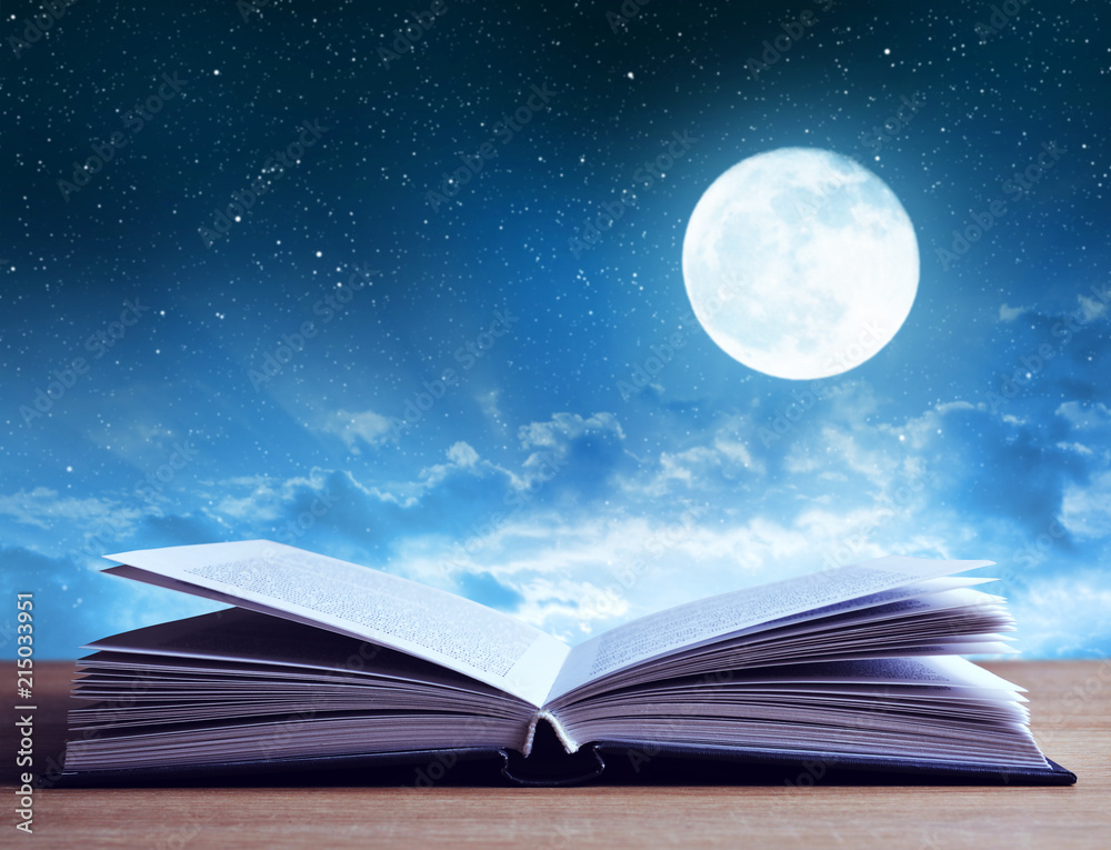 Naklejka premium Open book on wooden plank night sky with moon in the background. 