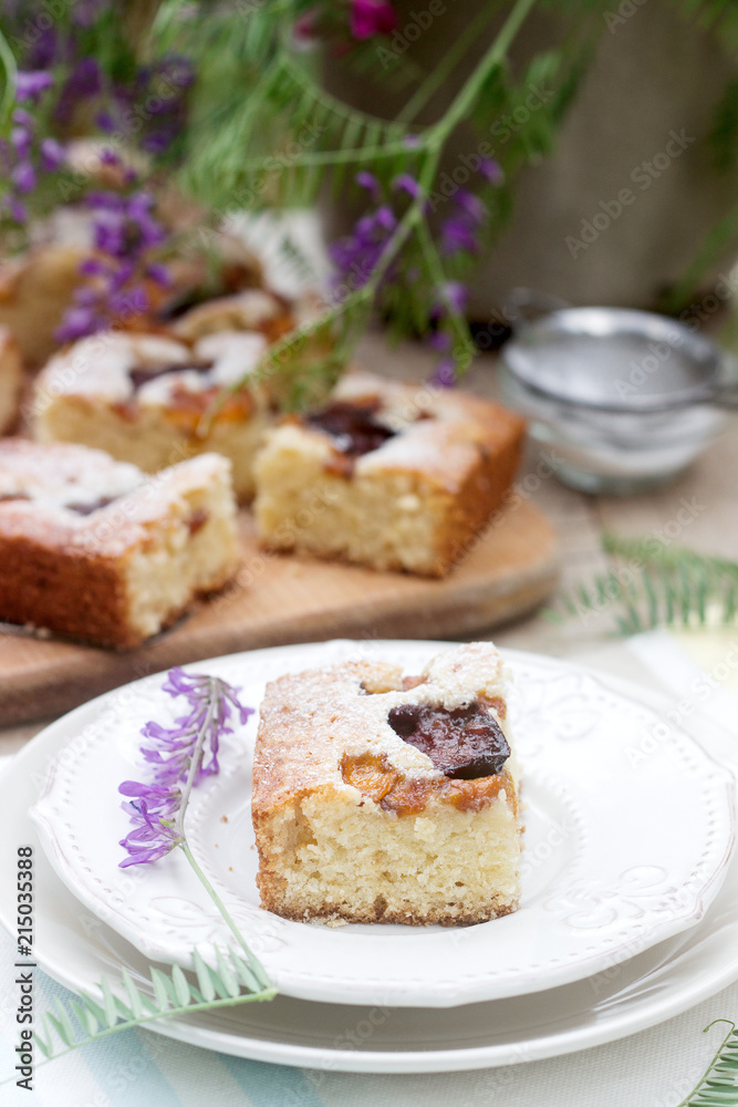 Pieces of fruit pie with pieces of plums and peach and a bouquet of flowers on a wooden table. Rustic style. Pieces of fruit pie with pieces of plums and peach and a bouquet of flowers on a wooden table. Rustic style.
