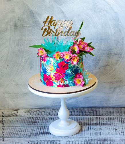 Tropical birthday cake on a cakestand with a topper