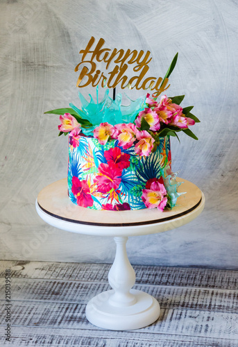 Tropical birthday cake on a cakestand with a topper