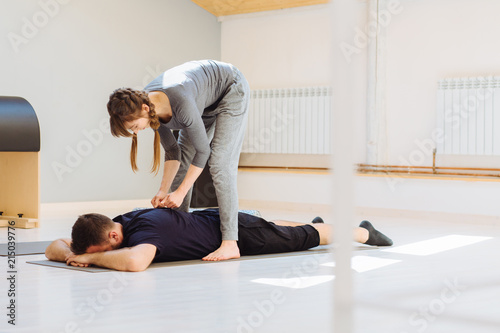 Back pain. Rehabilitation, back pain. Female instructor relaxing muscles of back for male patient. Rehabilitation after trauma concept.