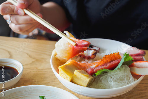 hokkigai in chopsticks, Eating Sashimi Rice Bowl Chirashi Don Japanese food photo