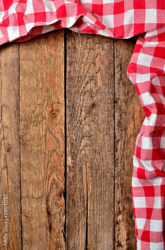 Red checkered tablecloth top and right frame on vintage wooden table background - view from above - vertical photo