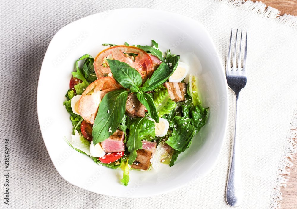 Salad with grilled tuna, quail eggs and fresh vegetables in white plate Salad with grilled tuna, quail eggs and fresh vegetables in white plate