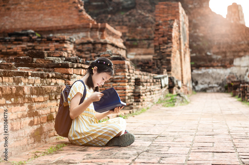 Asian cute girl relaxing outdoors while read history book,Student enjoy learning at historical, park,Wat Mahathat,Ayutthaya,Thailand