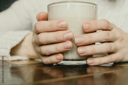 Closeup of woman's hands holding cup with warm beverage, selective focus