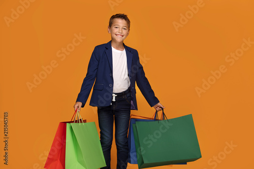 Little boy with colorful shopping bags smiling.