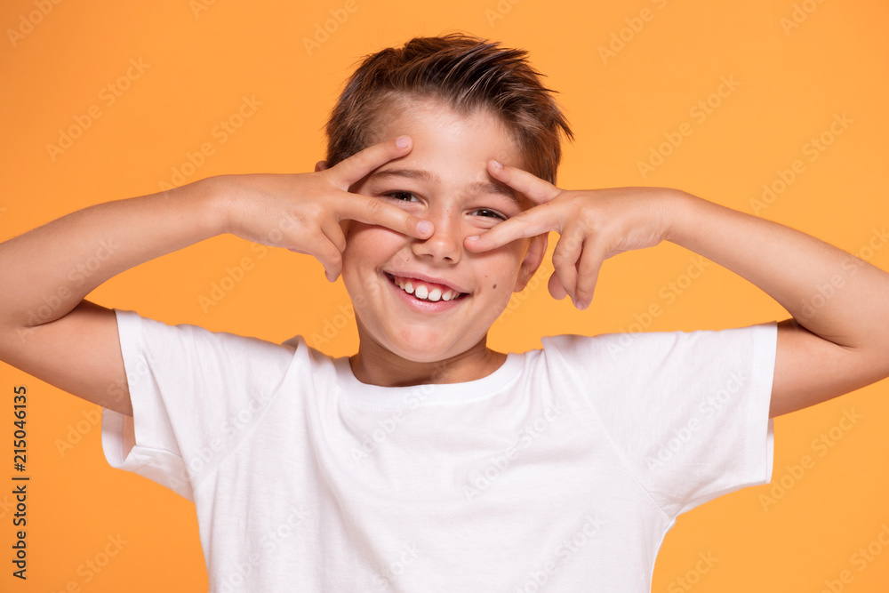 Young emotional little boy on orange studio background. Young emotional little boy on orange studio background.