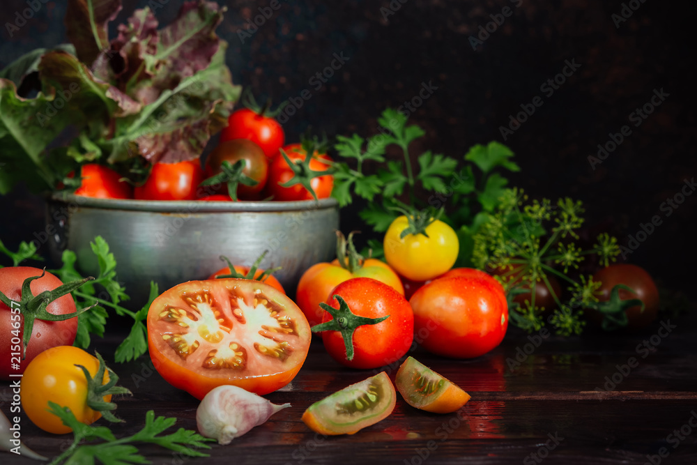 Fresh tomatoes and parsley, dill, garlic on a dark background in a rustic kitchen and wooden utensils still life with copy space Fresh tomatoes and parsley, dill, garlic on a dark background in a rustic kitchen and wooden utensils still life with copy space