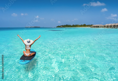 Glückliche Frau auf einen Surfbrett treibt über den türkisen Gewässern der Malediven und genießt ihren Sommerurlaub