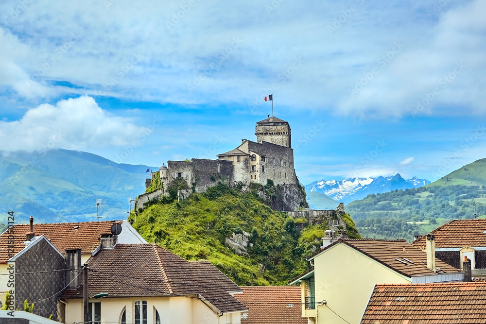 Chateau Fort of Lourdes. Castle on a rock. Snowy mountain peaks. Blue sky with white clouds. City in the Hautes-Pyrénées, France Chateau Fort of Lourdes. Castle on a rock. Snowy mountain peaks. Blue sky with white clouds. City in the Hautes-Pyrénées, France
