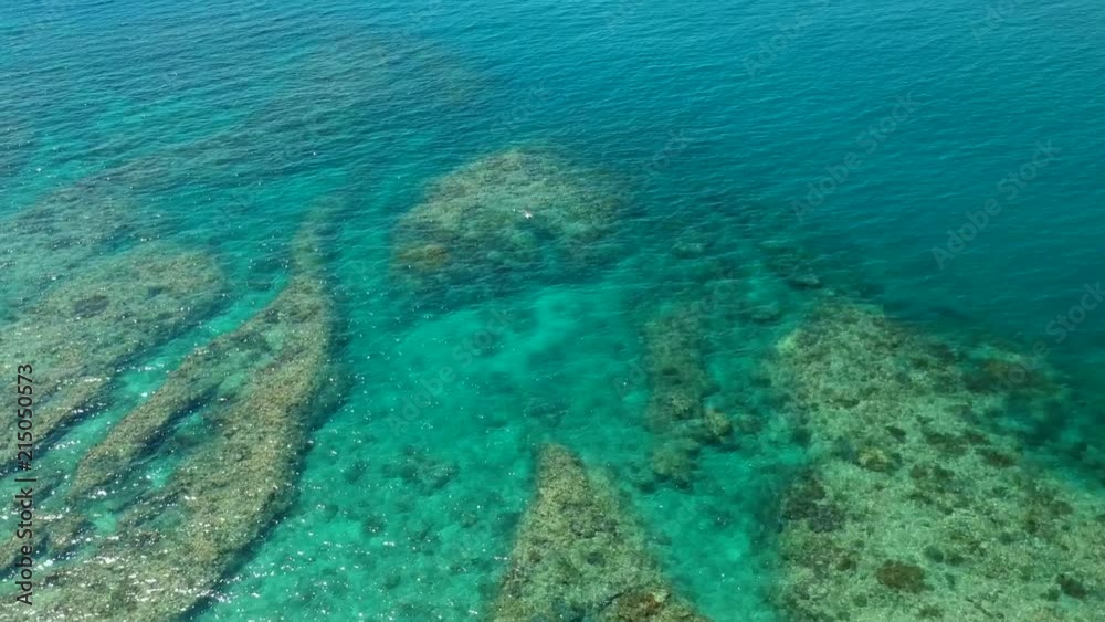 A rising drone shot of 2 snorkelers fining over coral reef in clear turquoise water A rising drone shot of 2 snorkelers fining over coral reef in clear turquoise water