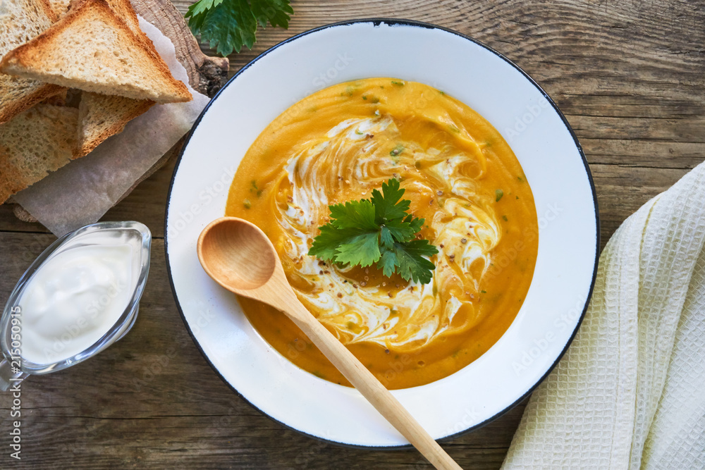 Carrot soup with sour cream and parsley in a bowl Carrot soup with sour cream and parsley in a bowl