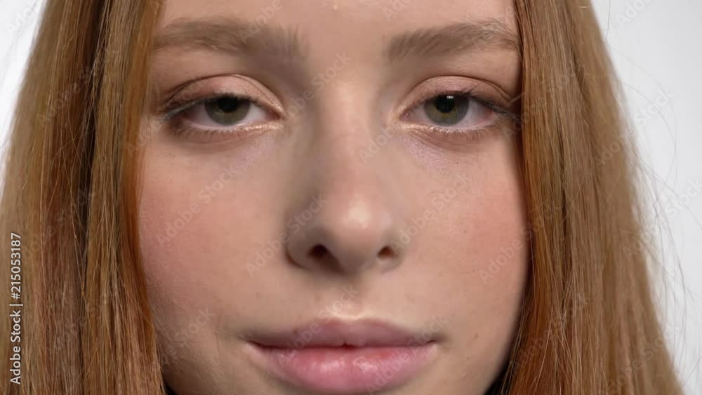 Face of young sweet calm ginger girl is watching at camera, white background Face of young sweet calm ginger girl is watching at camera, white background