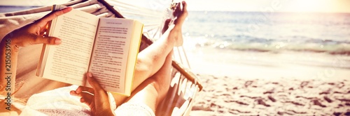 Brunette reading book while relaxing on hammock photo