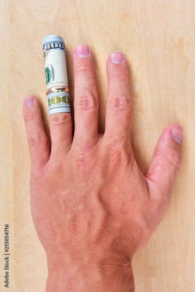 Marriage of convenience. 100 dollar banknote wrapped with a roll on a ring finger