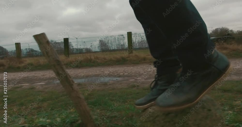 A hiker is walking on stones next to a country road.