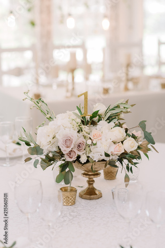 Beautiful flowers in a golden vase on a white table.