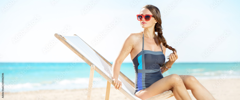 young woman looking into distance while sitting in beach chair