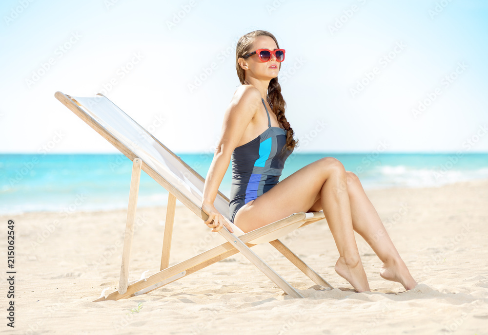 young woman looking into distance while sitting in beach chair