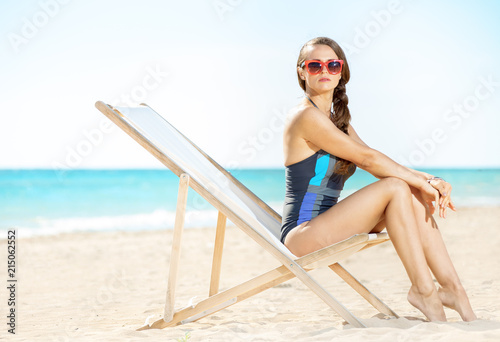 young woman in beachwear on beach sitting in beach chair