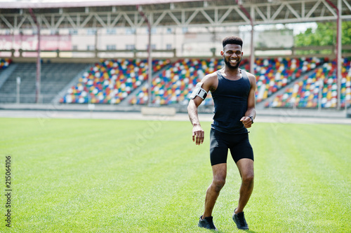 African american male athlete in sportswear doing jump exercise at stadium.