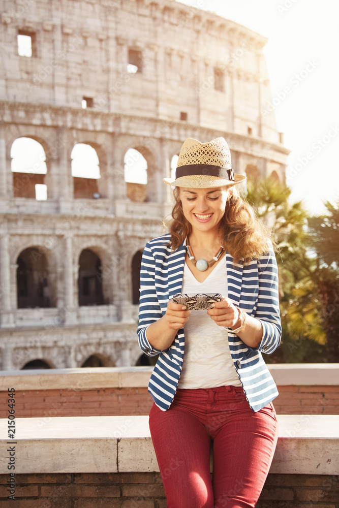 smiling stylish tourist woman in Rome, Italy writing sms