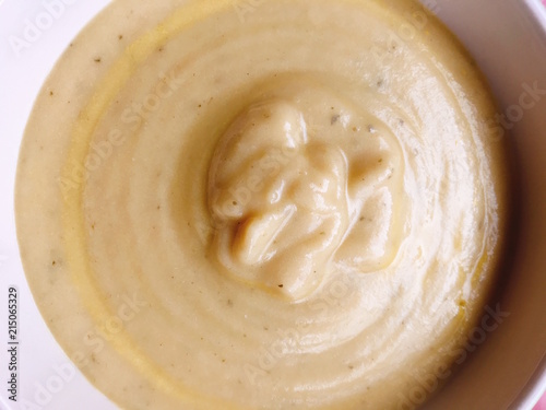 Top view of a cream soup of Zucchini and vegetables in a white bowl