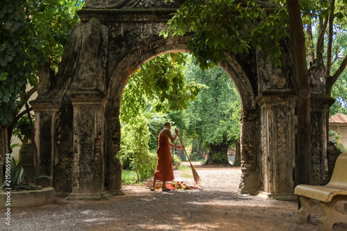 Buddhist monks sweeping under a stone arch in Buddhist temple in cambodia