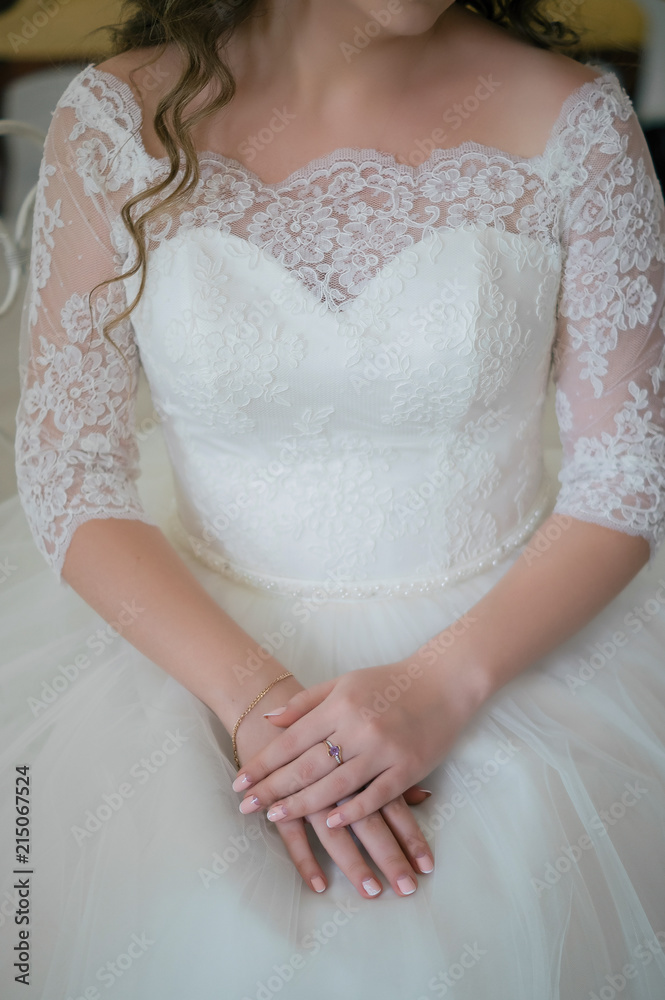 Close up of bride folded her hands on her lace wedding dress