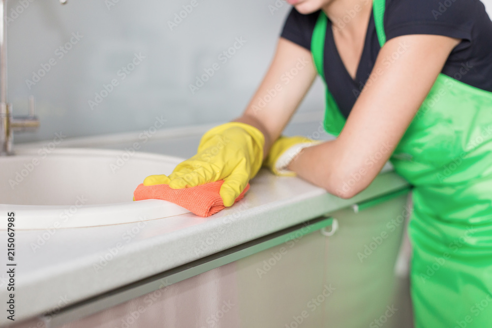 Obraz premium Closeup of female hands in rubber yellow gloves cleaning the cooker panel at home kitchen. Home, housekeeping concept. cleaning service