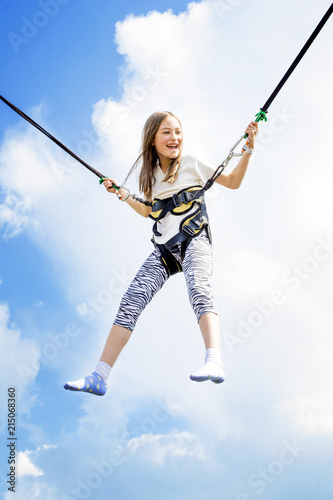 Little girl bouncing high in the air using a bungee trampoline.