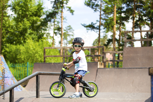 Happy boy on a bicycle with sunglasses, helmet and protective gear