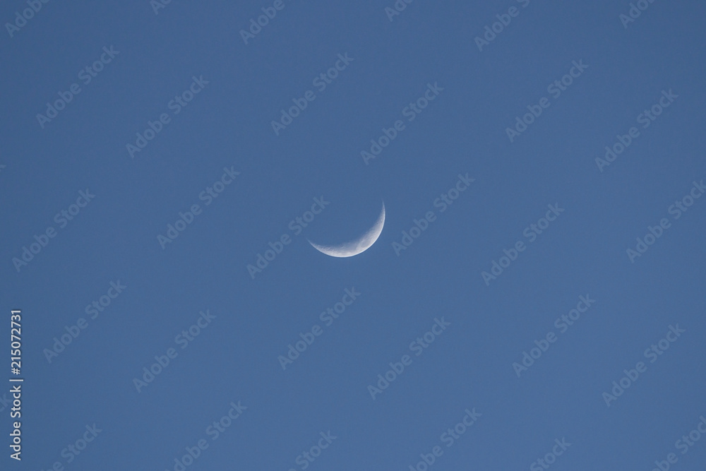 A crescent moon in the center of blue sky A crescent moon in the center of blue sky