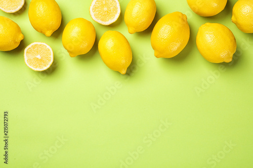 Flat lay composition with whole and sliced lemons on color background