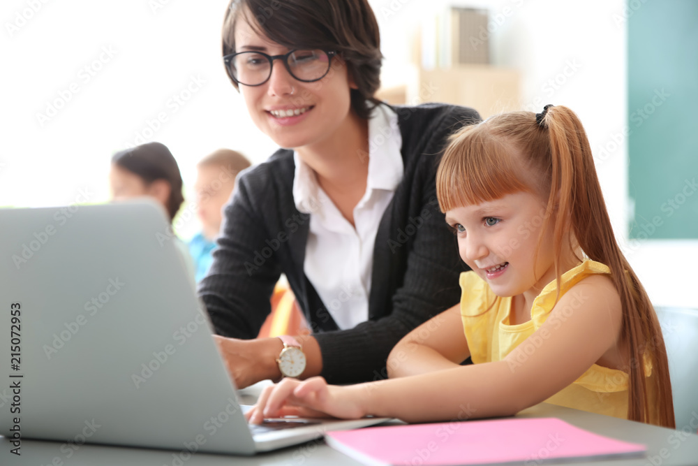 Female teacher helping child with assignment at school Female teacher helping child with assignment at school