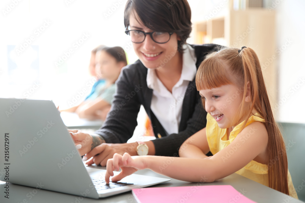 Female teacher helping child with assignment at school Female teacher helping child with assignment at school