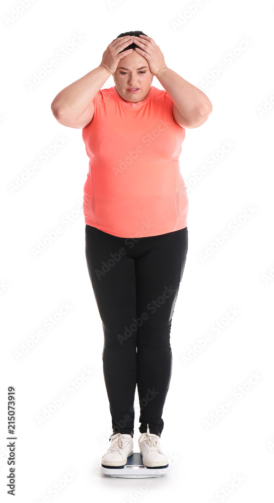 Overweight woman in sportswear using scales on white background