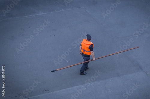 a well-equipped sailor holds a large stick in his hand to help a ship stand or repel at a port. port workers provide the ships.
