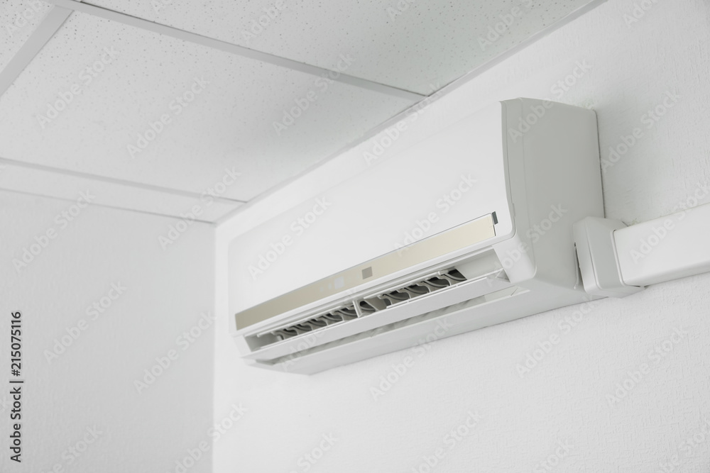 Modern air conditioner on white wall indoors Modern air conditioner on white wall indoors