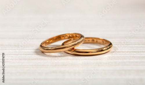 Two golden wedding rings on white wooden background