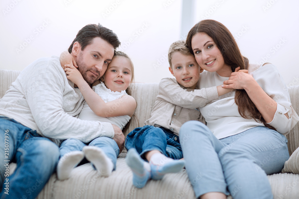 parents hug their children sitting on the couch