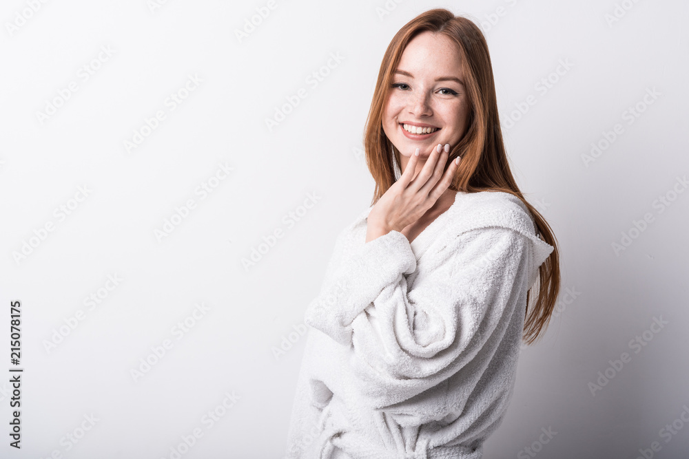 Beautiful red-haired girl in a white bathrobe on a light background Beautiful red-haired girl in a white bathrobe on a light background