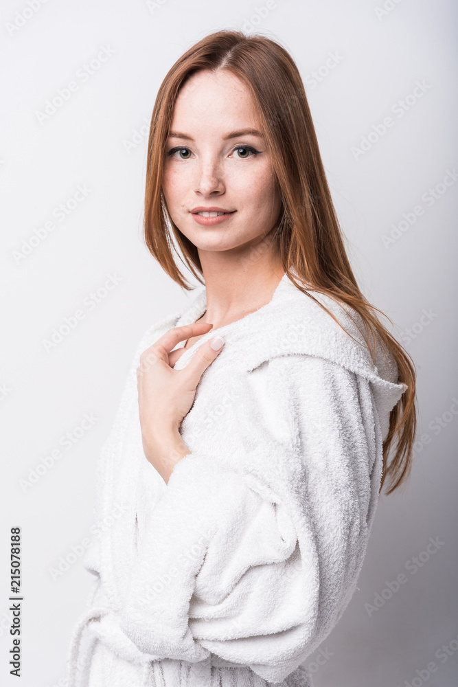 Beautiful red-haired girl in a white bathrobe on a light background Beautiful red-haired girl in a white bathrobe on a light background