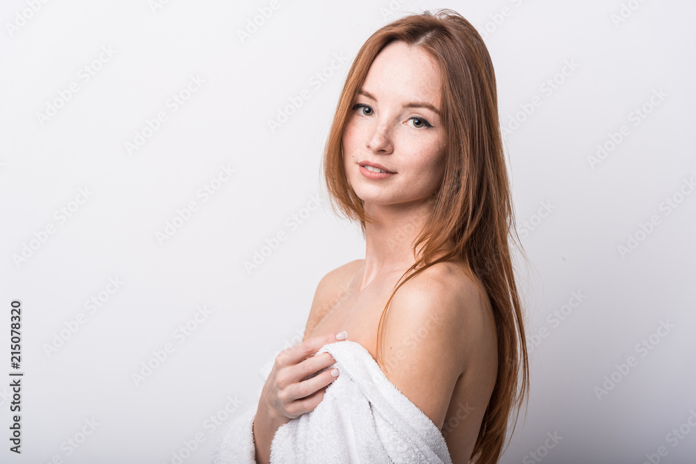 Beautiful red-haired girl in a white bathrobe on a light background Beautiful red-haired girl in a white bathrobe on a light background