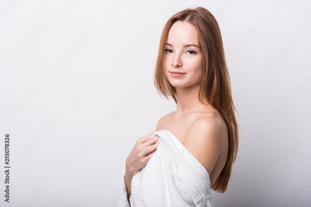 Beautiful red-haired girl in a white bathrobe on a light background Beautiful red-haired girl in a white bathrobe on a light background