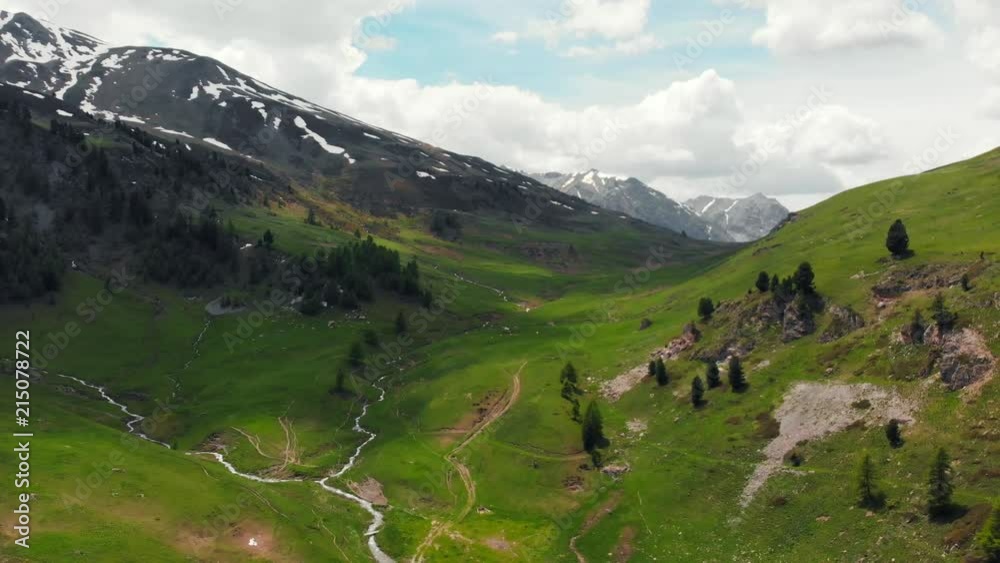 Aerial: flying over alpine valley, scenic waterfall snowcapped mountain range and dramatic road on the Italian Alps, adventure road trip in summer. Aerial: flying over alpine valley, scenic waterfall snowcapped mountain range and dramatic road on the Italian Alps, adventure road trip in summer.